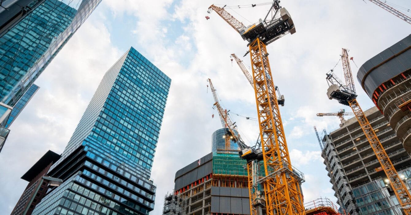 Construction site with cranes among high-rise buildings against a cloudy sky, indicating Vietnam’s Construction Safety Standards.