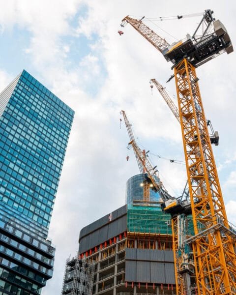 Construction site with cranes among high-rise buildings against a cloudy sky, indicating Vietnam’s Construction Safety Standards.