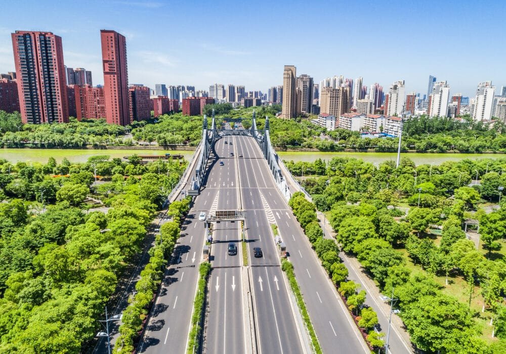 Aerial view of a bridge with cars over a river in a metropolitan area with greenery and high-rises to symbolise Urbanization and Construction Vietnam.