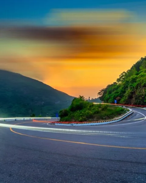 Hai Van Pass: Curvy mountain road with light trails at dusk in Vietnam, symbolising Public-Private Partnerships Vietnam projects.