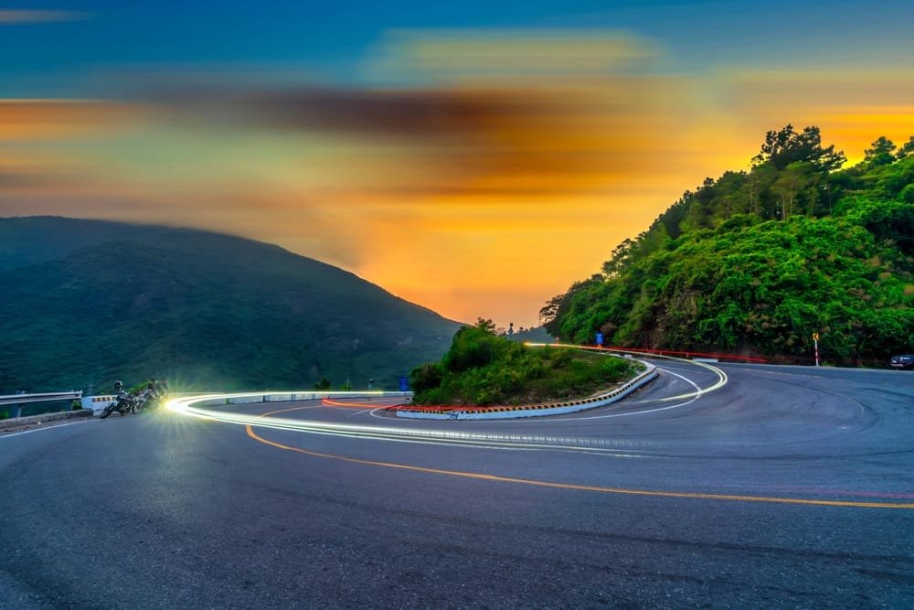 Hai Van Pass: Curvy mountain road with light trails at dusk in Vietnam, symbolising Public-Private Partnerships Vietnam projects.