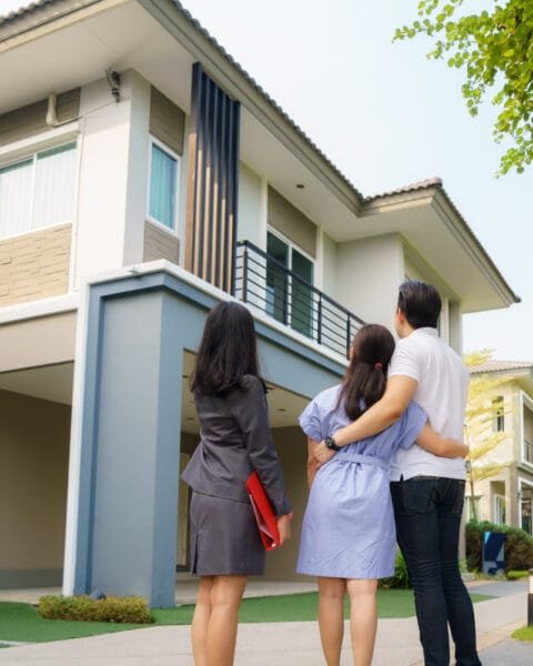 A family looking at a modern two-story house, possibly considering it as their new home to indicate the Urban Real Estate Market Vietnam.